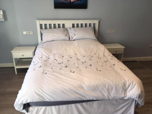 霍姆弗斯Swans Nest的一张带白色棉被和鲜花的床