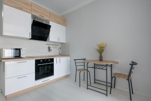 基辅Comfort House的厨房配有白色橱柜和桌椅