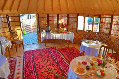 卡拉科尔Happy Nomads Yurt Camp & Hostel的一间带桌椅的用餐室和一间带桌面的用餐室