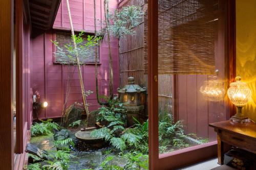 金泽金泽菊乃雅町屋的一座花园,位于一座带喷泉的粉红色房子前面