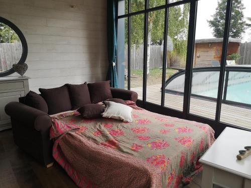 Les RosiersLa Cabane Bois des Roses的一间卧室设有一张床和一个大窗户
