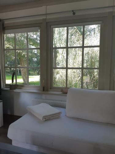AssendelftB&B Saense huisje的窗户前的白色床和2条毛巾
