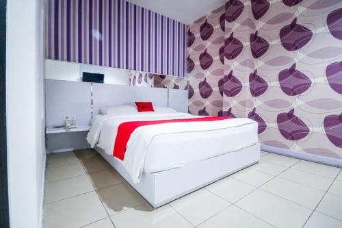 巴厘巴板RedDoorz near Terminal Batu Ampar的卧室配有白色的床和紫色的墙壁