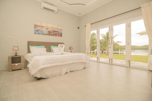 沙璜The Hawk's Nest Resort的白色卧室设有大床和滑动玻璃门