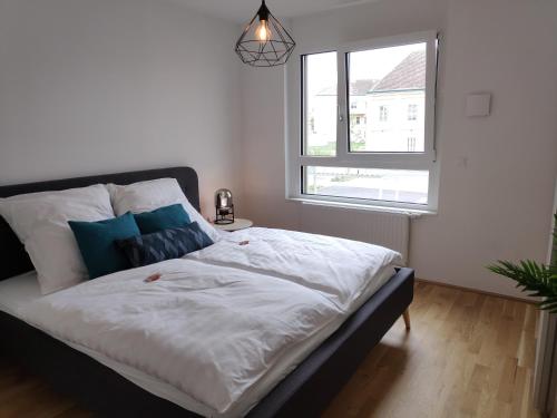 施韦夏特City Appartement Wien-Schwechat的一间卧室配有一张带白色床单的床和一扇窗户。
