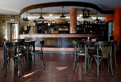San Mamede de Carnota奥普鲁索旅馆的一间带桌椅的餐厅和一间酒吧