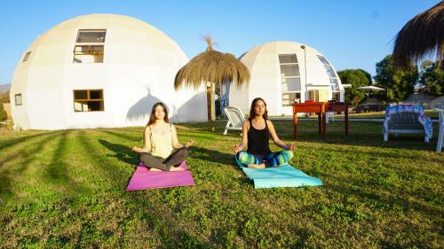 拉塞雷纳Domos Dream的两个坐在草地上,在圆顶前做瑜伽的女人