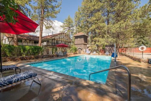 大熊湖黑森林旅馆的一座房子旁的游泳池,配有红色遮阳伞