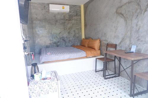 苏安庞班帕爵穆素安蓬旅馆的一间小卧室,配有一张床和一张桌子