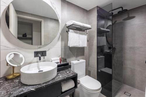 堪培拉Deco Hotel Canberra的一间带水槽、卫生间和镜子的浴室