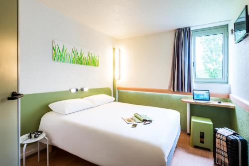 埃鲁维尔圣克莱宜必思卡昂爱荷维耶经济酒店的酒店客房配有一张白色大床和一台笔记本电脑