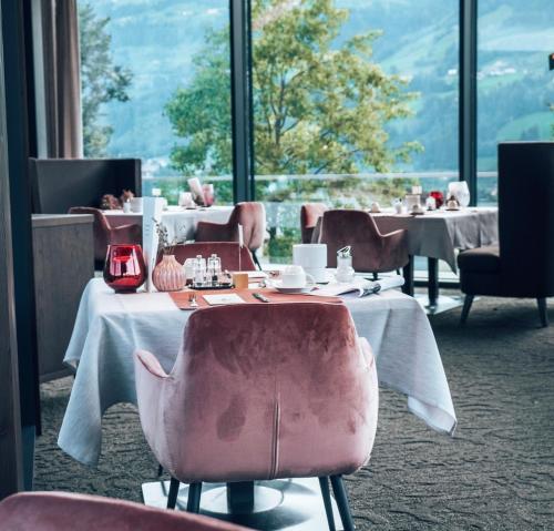 菲根黑尔德运动疗养四星级酒店的一间带桌椅的用餐室和大窗户