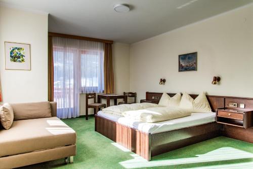 巴特霍夫加施泰因莫努斯公寓酒店的一间卧室配有两张床、一张沙发和一把椅子
