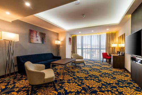 埃里温Ramada Hotel & Suites by Wyndham Yerevan的酒店客房设有沙发、椅子和电视。