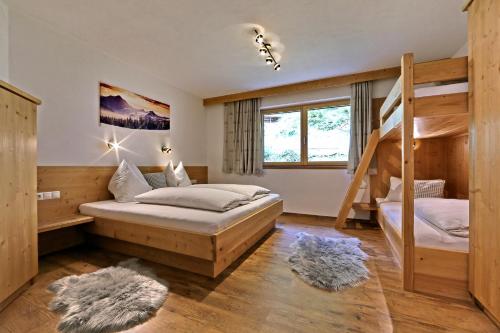 策尔贝格Apart Bergkristall Zellberg的一间卧室设有两张双层床和梯子