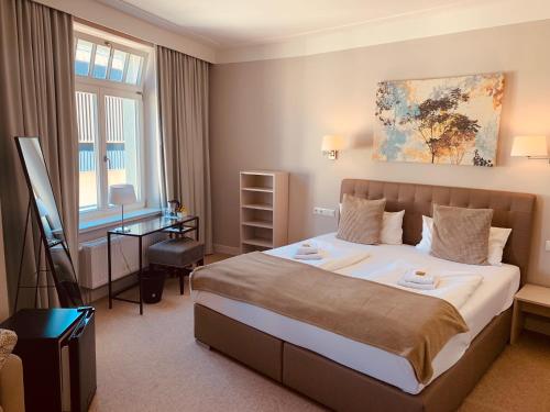莱比锡林德瑙酒店的酒店客房设有一张大床和一张书桌。