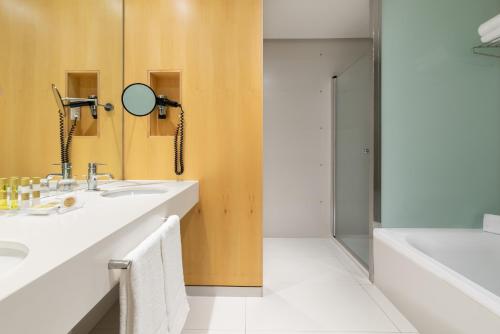 奥维多Eurostars Palacio de Cristal的浴室配有盥洗盆、镜子和浴缸