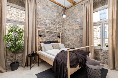 里耶卡Molo Longo - Central Apartments & Rooms的一间卧室设有石墙、一张床和窗户
