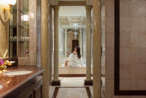 曼谷The Emerald Hotel - SHA Extra Plus的女人在浴室里看着镜子中的自己