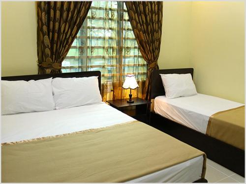 关丹Villasuri Homestay的酒店客房设有两张床和窗户。