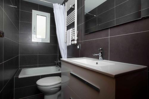 锡切斯Apartamentos Sunway Talaia的一间带水槽、卫生间和镜子的浴室