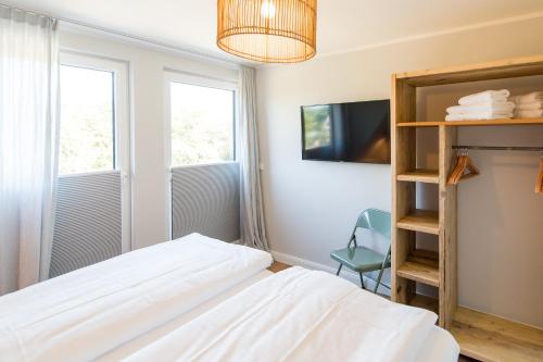 韦斯特兰Welle 11 Sylt的一间卧室设有一张床、一台电视和两个窗户。