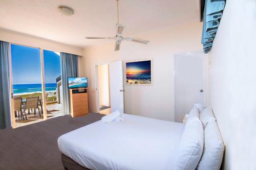 黄金海岸可伦宾海滩沙堡酒店的卧室配有白色床,享有海景
