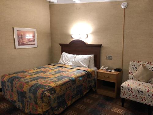 北锡拉丘兹锡拉丘兹机场红地毯旅店的配有一张床和一把椅子的酒店客房