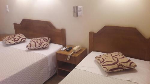 里斯本阿利坎特酒店的一间设有两张床和一张桌子上的电话的房间