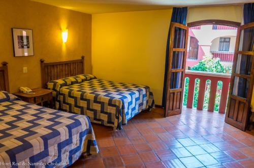 乔卢拉Hotel Real de Naturales的酒店客房设有两张床和窗户。