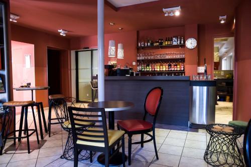 罗纳河畔的图尔农Logis Hôtel Restaurant Azalées的餐厅内带桌椅的酒吧