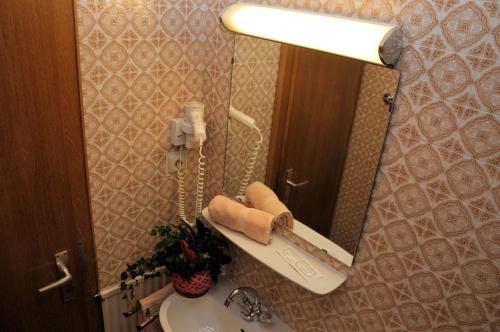 加尔蒂Pension Belvedere的一间带水槽的浴室和镜子内的电话