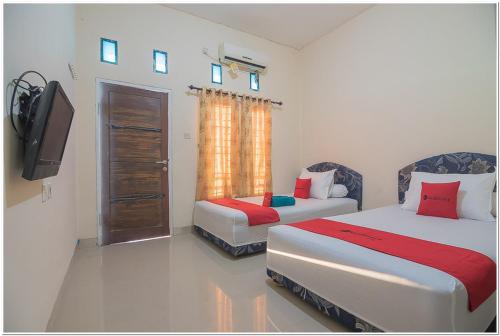 巴厘巴板RedDoorz near Lapangan Tenis Balikpapan的一间卧室配有两张床、一台电视和一台电视。