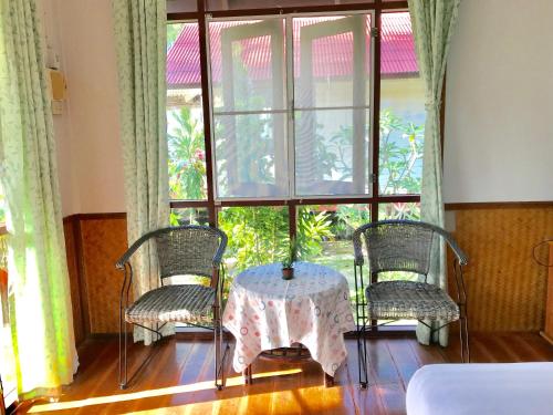 湄南海滩Mali House的客房设有桌子、两把椅子和窗户。