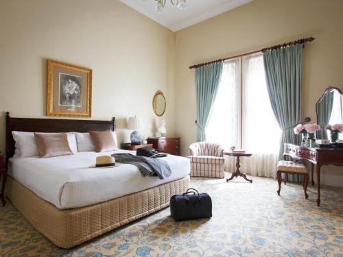墨尔本温莎酒店 的一间卧室配有一张床、一张桌子和一架钢琴
