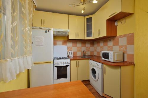 鄂木斯克Omsk Sutki Apartments on Maslennikova 26的厨房配有白色家电和黄色橱柜