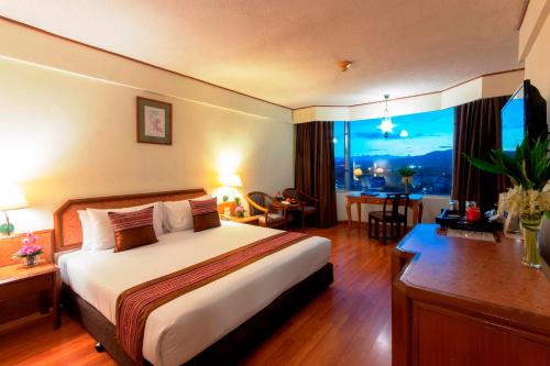 清迈Duangtawan Hotel Chiang Mai -SHA Extra Plus的配有一张床、一张书桌和一扇窗户的酒店客房