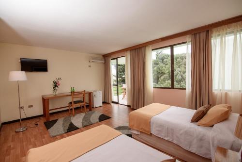 阿里卡Hotel del Valle Azapa的一间卧室设有两张床、一张桌子和窗户。