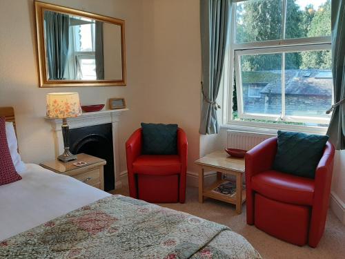 鲍内斯温德米尔五月小屋住宿加早餐旅馆的一间卧室配有两张红色椅子、一张床和窗户