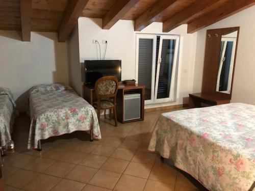 LuniAlbergo Antica Luni的一间卧室配有两张床、一张桌子和一把椅子
