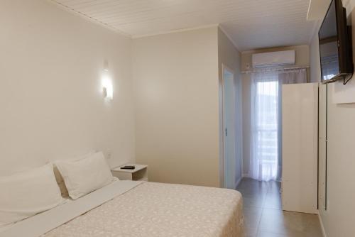 乌鲁比西Pousada das Flores UpSerra的白色的卧室设有床和窗户