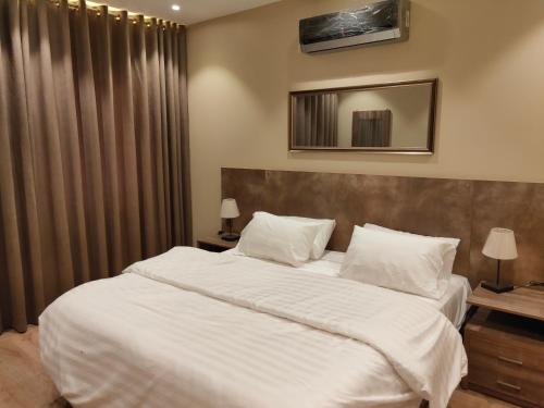 卡拉奇Hamsun Shahrah-e-Faisal的卧室配有一张带白色床单和枕头的大床。