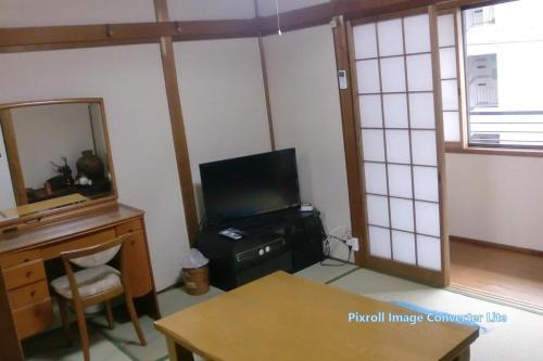 奈良Guesthouse Yoshikawa的配有电视、书桌和镜子的客房
