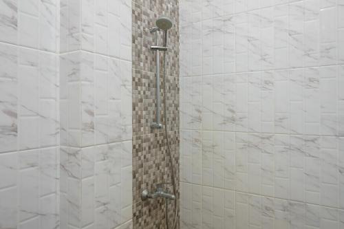 LubuklinggauRedDoorz Plus @ Hotel Sempurna Watervang Lubuk Linggau的浴室设有白色瓷砖淋浴。