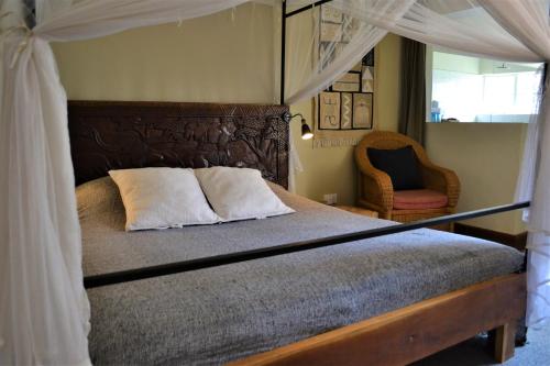 利隆圭Africa House Malawi的一间卧室配有一张天蓬床和一把椅子