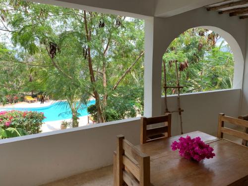 吉汶瓦Breeze Residence Apartments的一间设有桌子并享有游泳池景致的用餐室