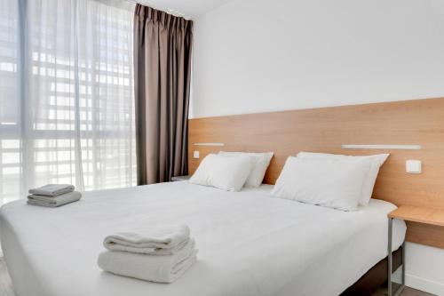 波尔多渣油加乐里塔特里酒店的一间卧室配有一张带白色床单的床和一扇窗户。