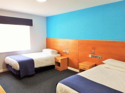 艾尔斯伯里The Olympic Lodge的酒店客房设有两张床和蓝色的墙壁。