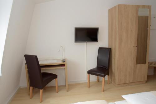 内卡河畔弗赖贝格Hotel - Restaurant Baumann的一间设有两把椅子、一张桌子和一台电视的房间