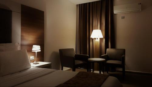 科纳克里Grand Hotel Central Conakry的酒店客房配有一张床、两把椅子和一张桌子